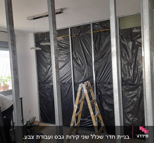 קירות גבס בבנייה עם מסגרת מתכת וסולם עץ